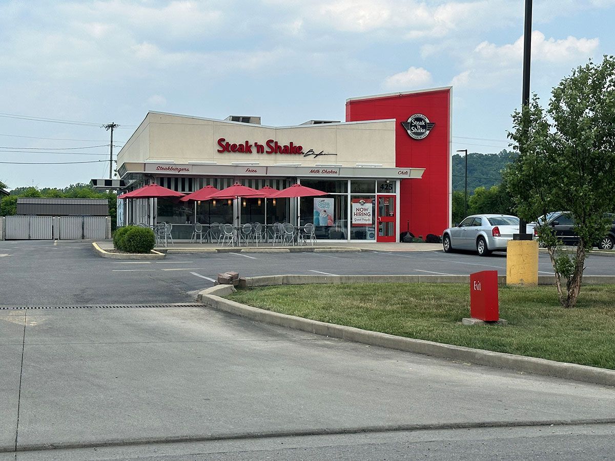 A steak n shake restaurant is located in a parking lot.