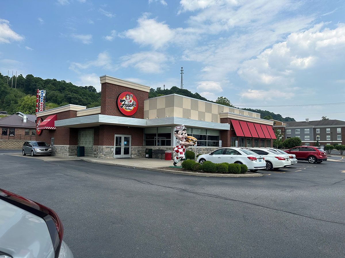 A restaurant with cars parked in front of it on a sunny day.