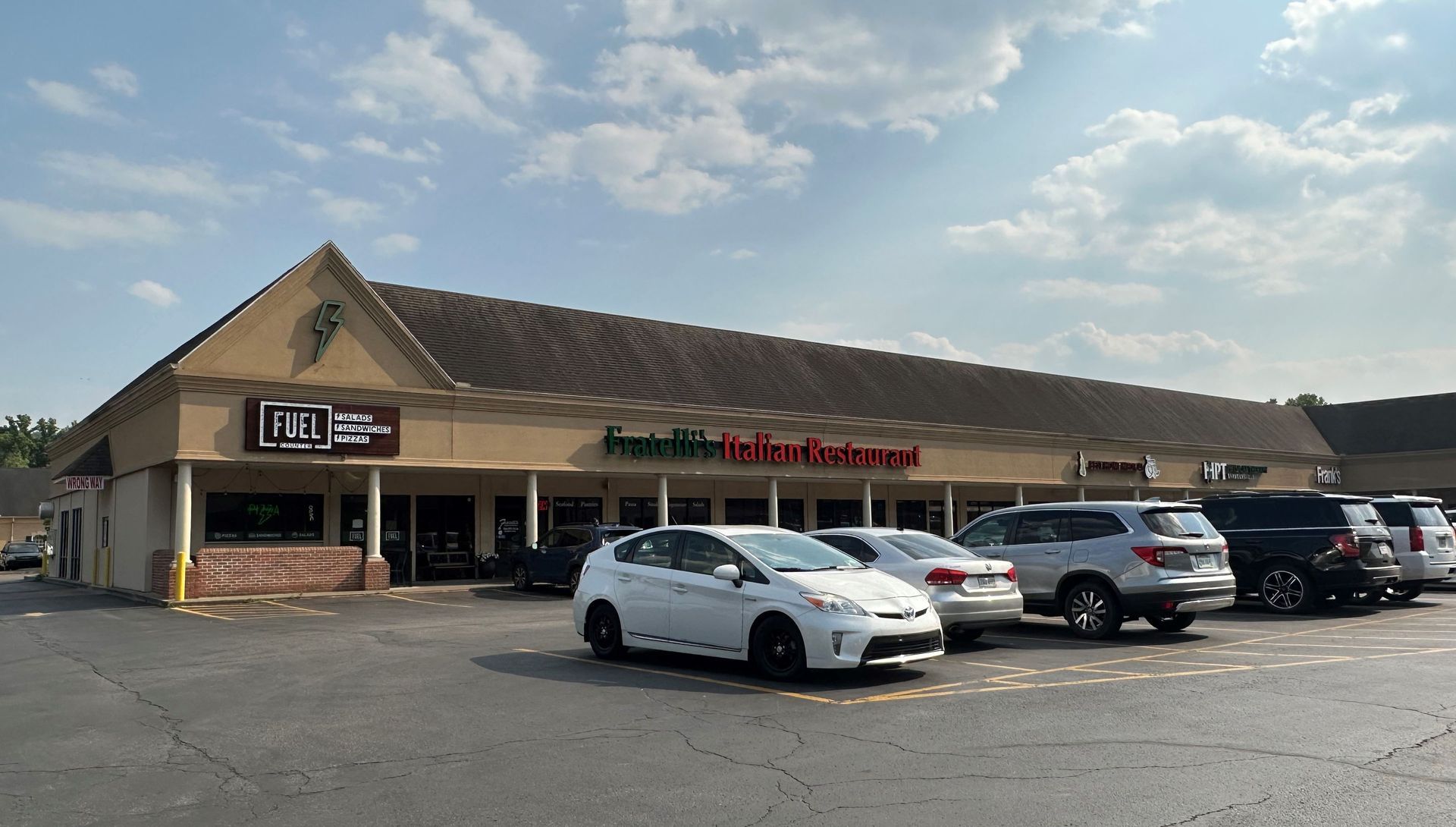 A lot of cars are parked in front of a store.
