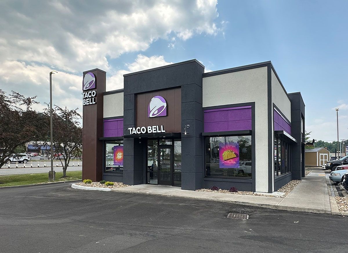 A taco bell restaurant is sitting in the middle of a parking lot.
