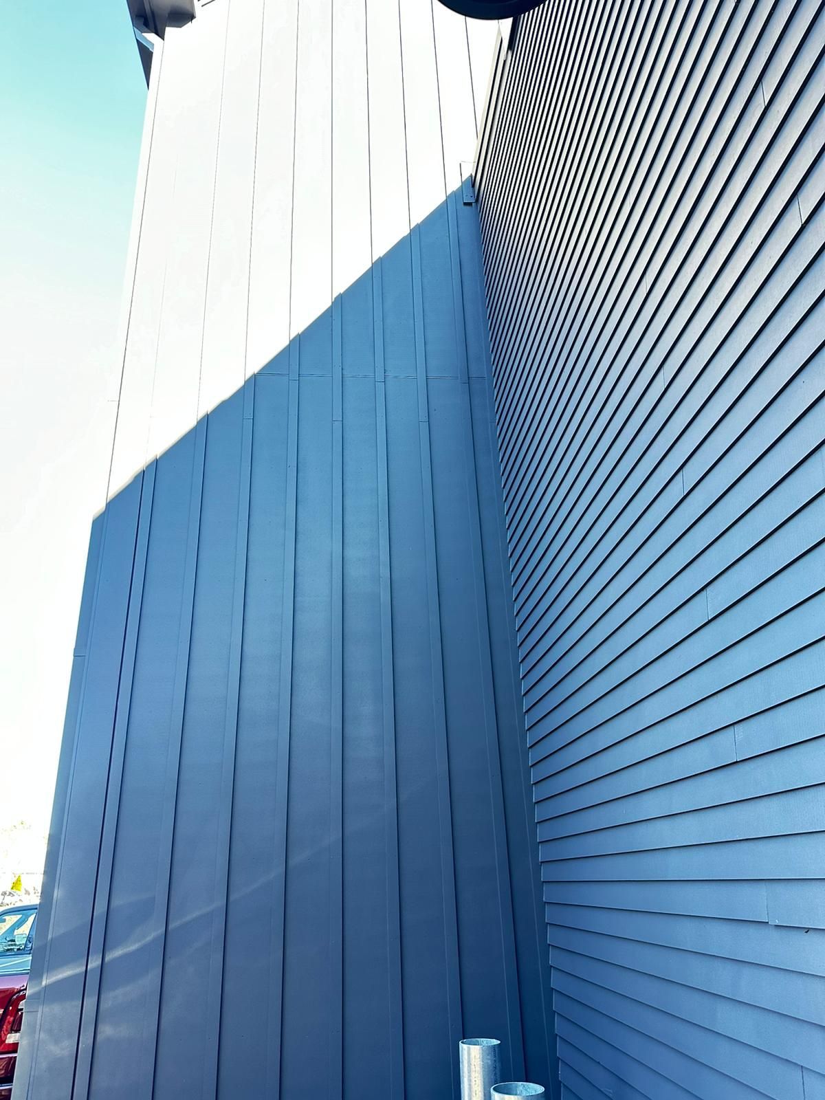 A large blue building with a red car parked in front of it