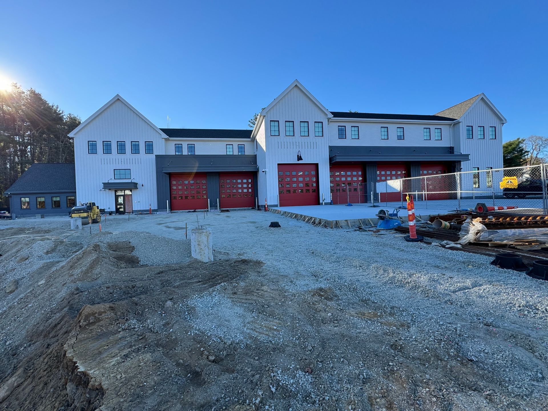 A large white building with red garage doors is under construction.