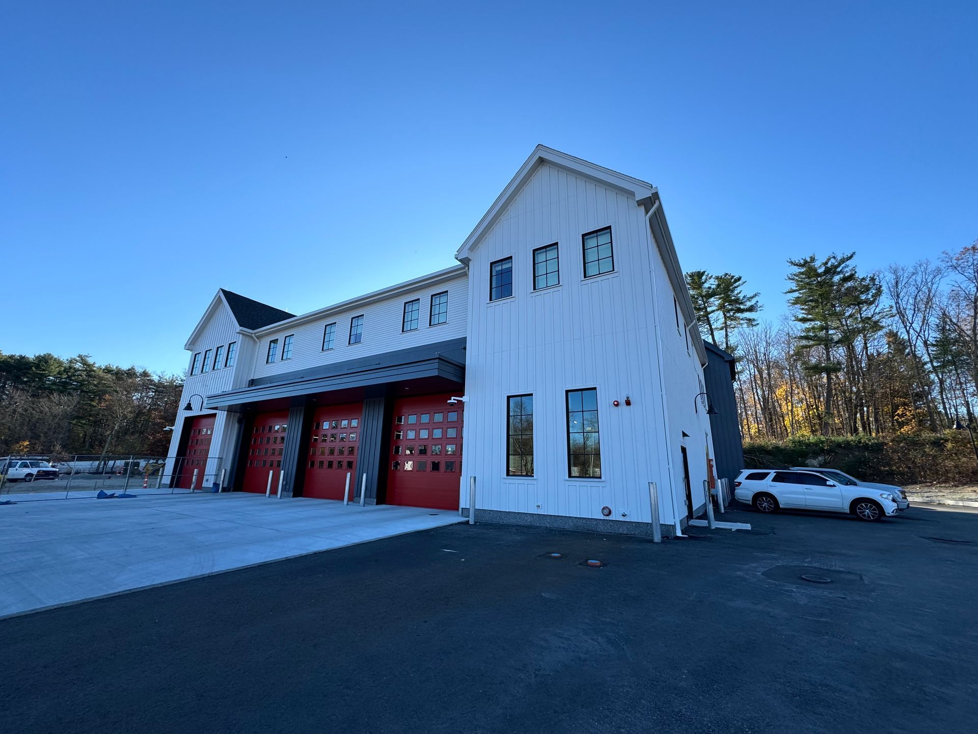 A white building with red doors and a car parked in front of it.