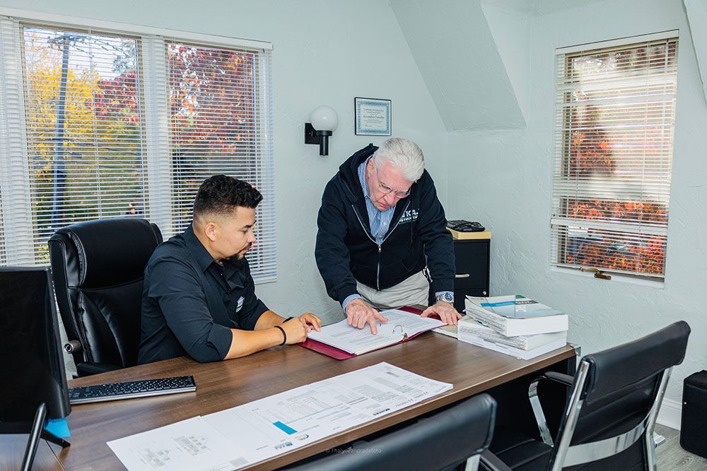 Two men are sitting at a table in an office looking at papers