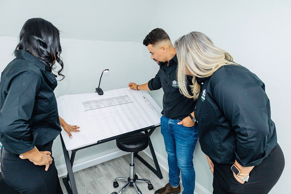 A group of people are standing around a table looking at a blueprint