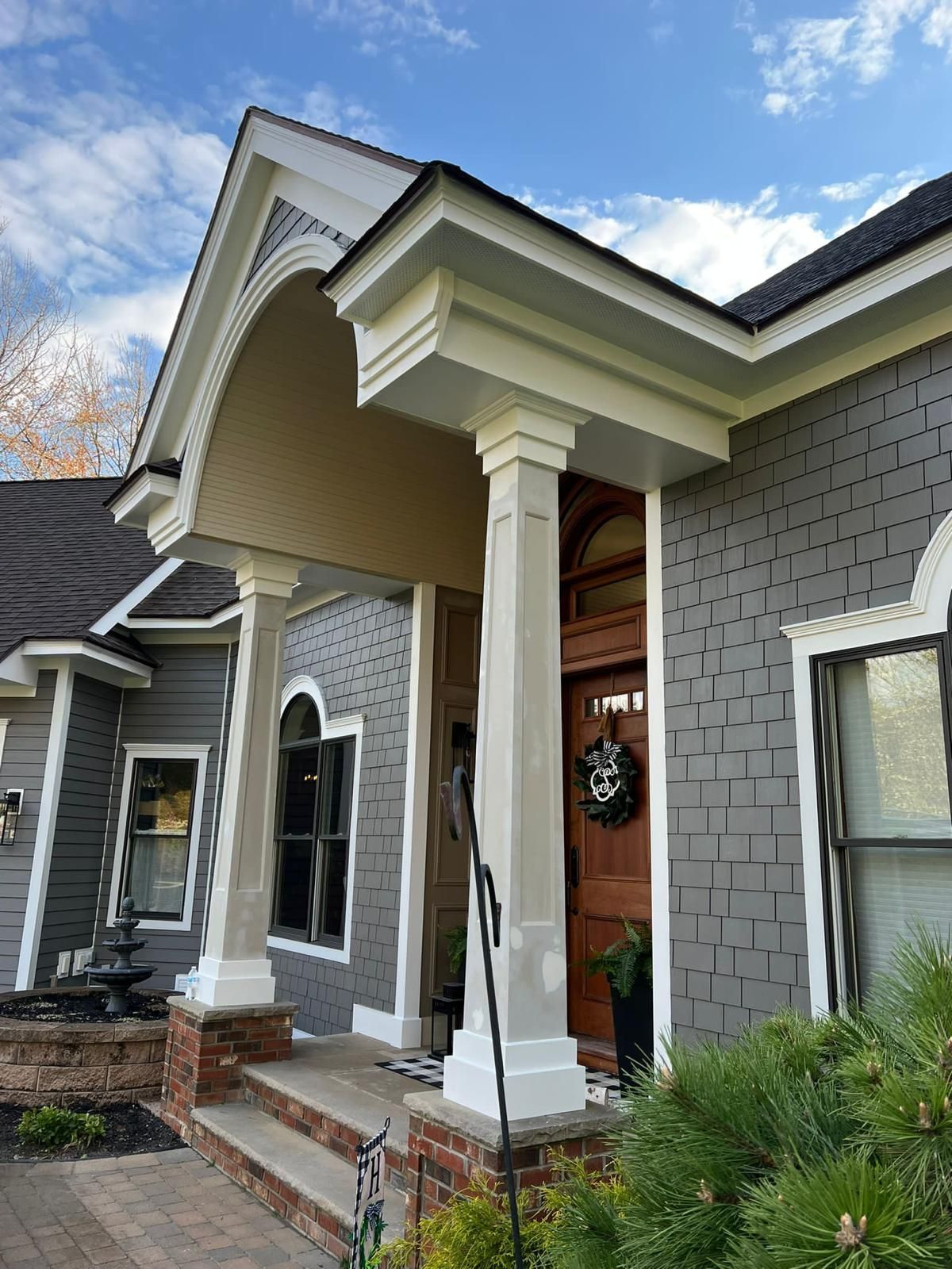 A front entrance of a house leads up to a beautiful wooden front door.