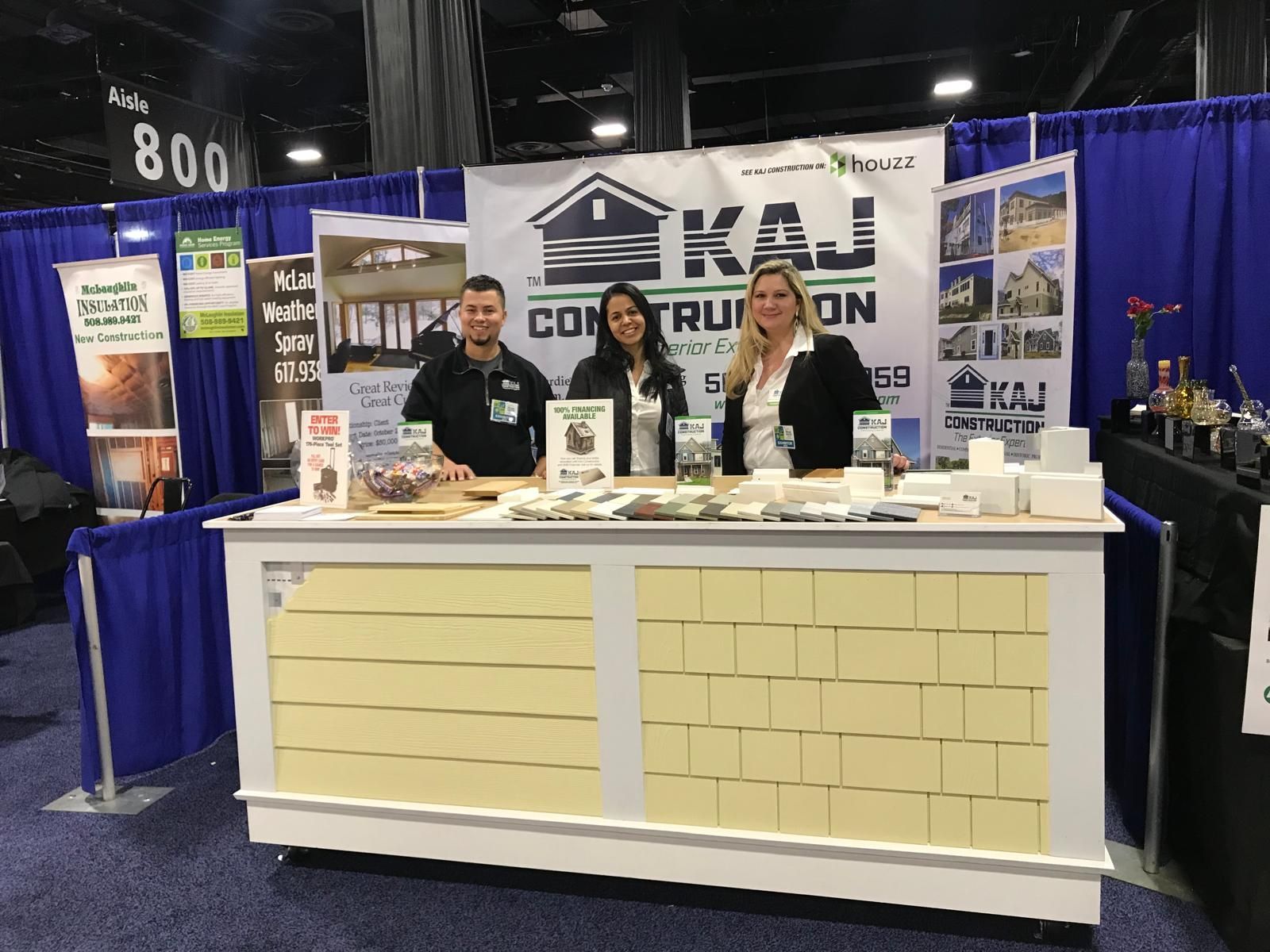 A group of people standing behind a counter at a construction show.