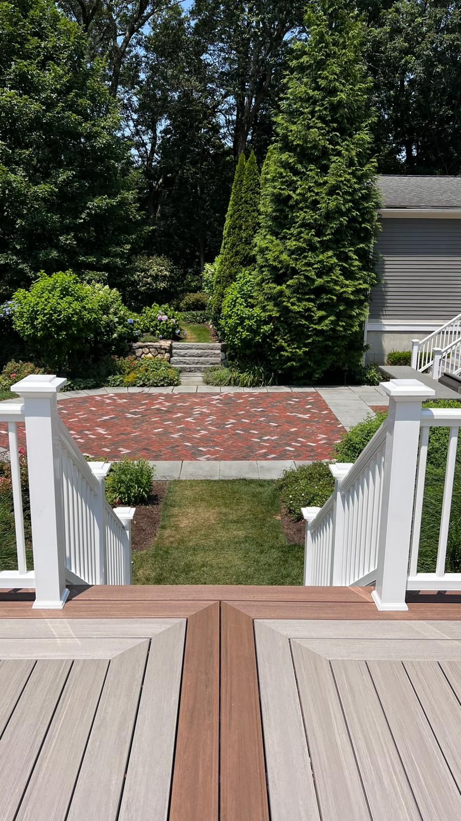 View from deck down to brick patio and garden steps.