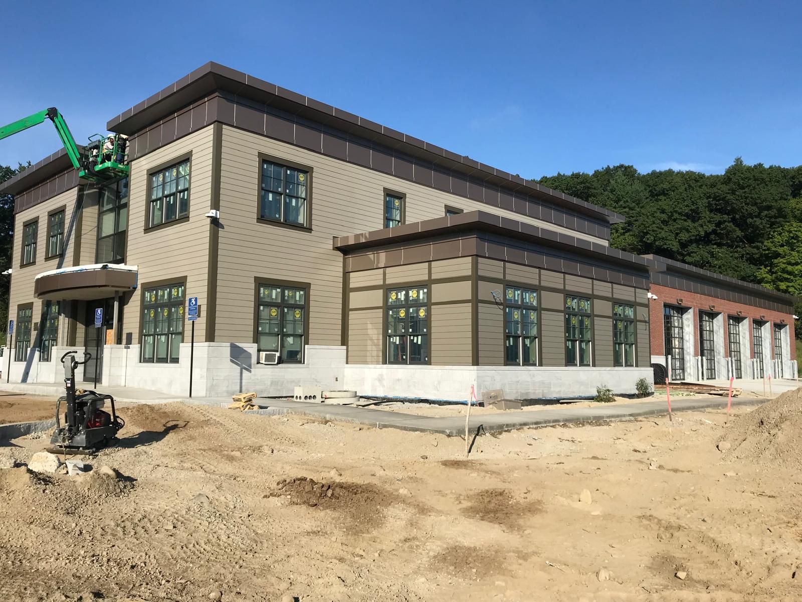A large building is being built in the middle of a dirt field.