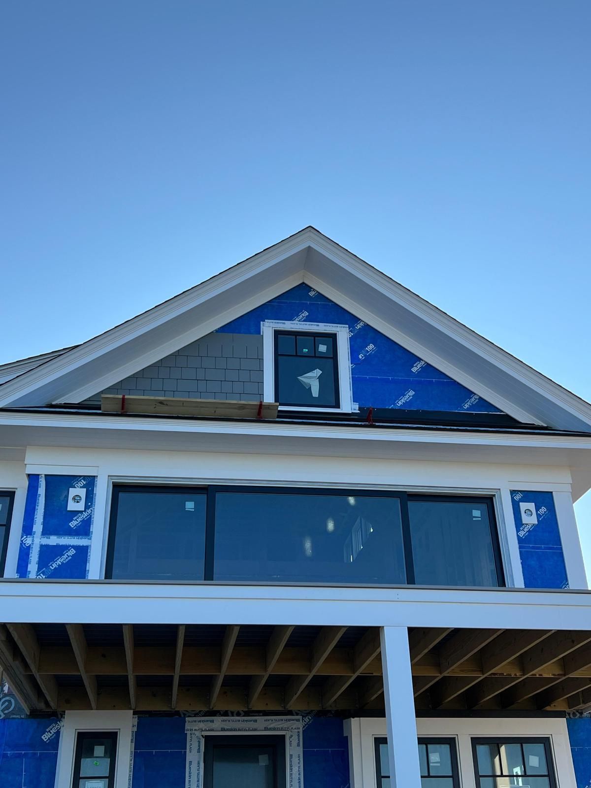A house is being built with blue siding and a blue sky in the background.