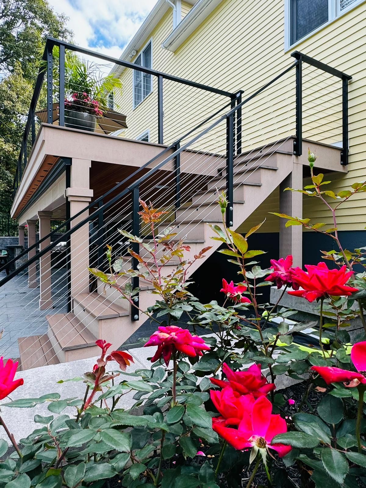 A deck with stairs and flowers in front of a house.