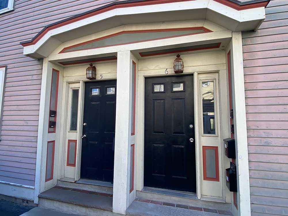 A pink house with two black doors and a porch.
