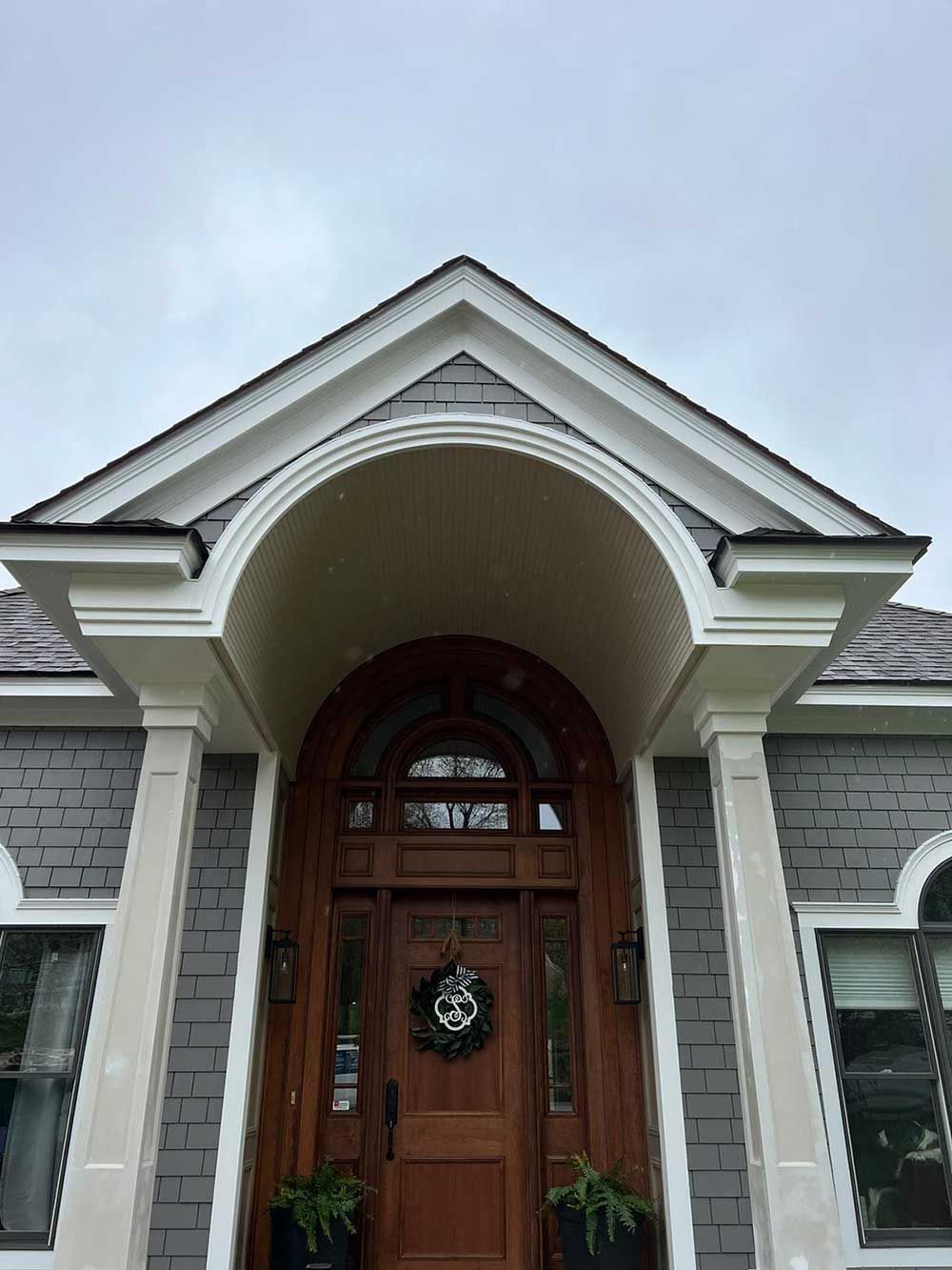 The front door of a house with a porch and a wreath on it.