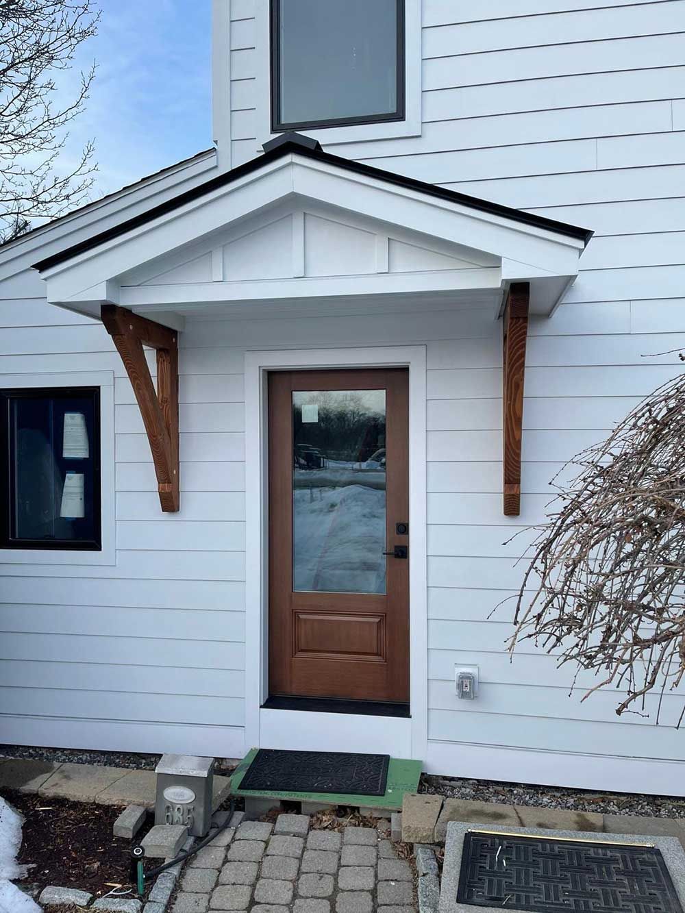 A white house with a wooden door and a porch.