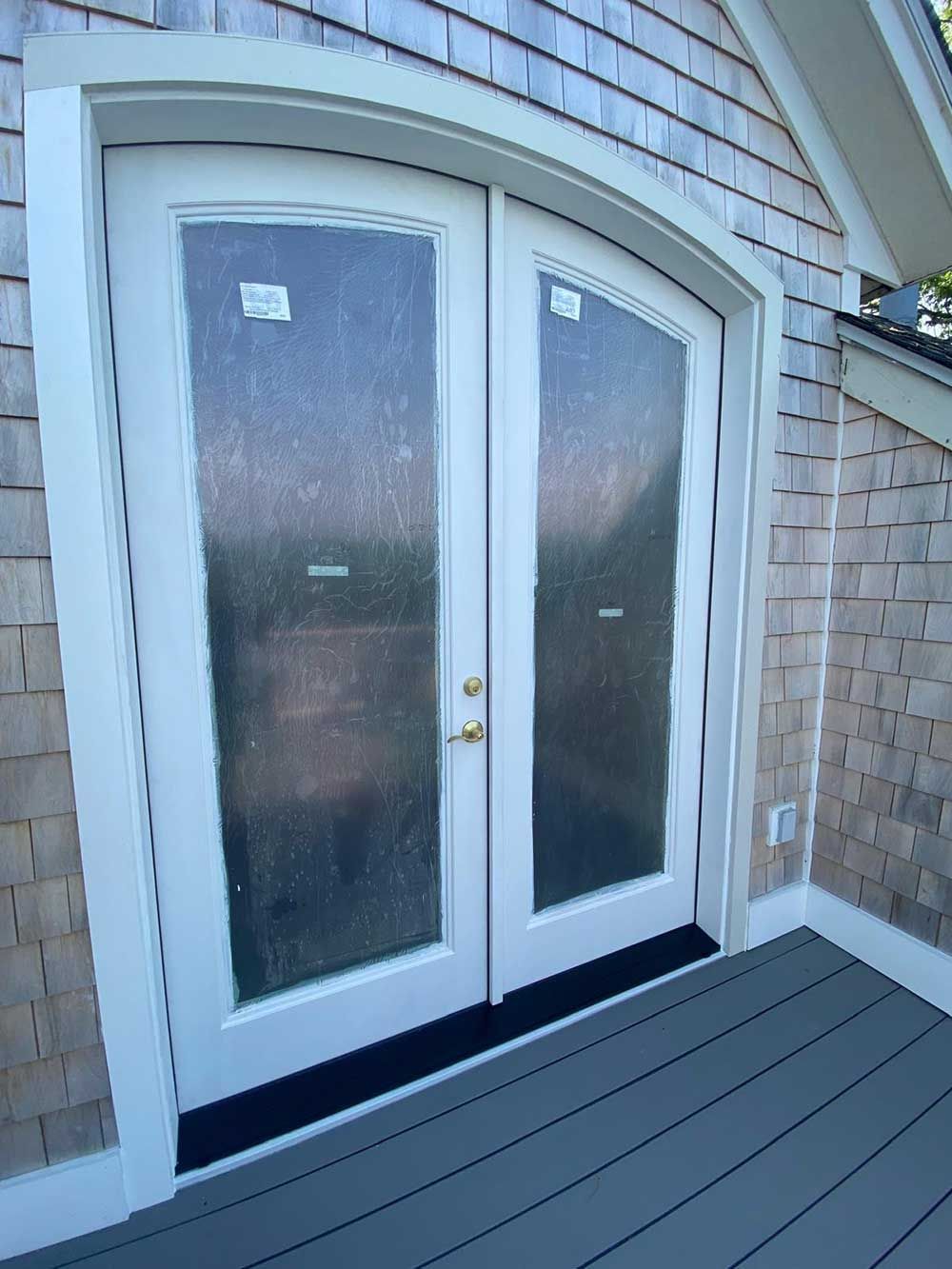 A white door with a curved arch on the side of a house.
