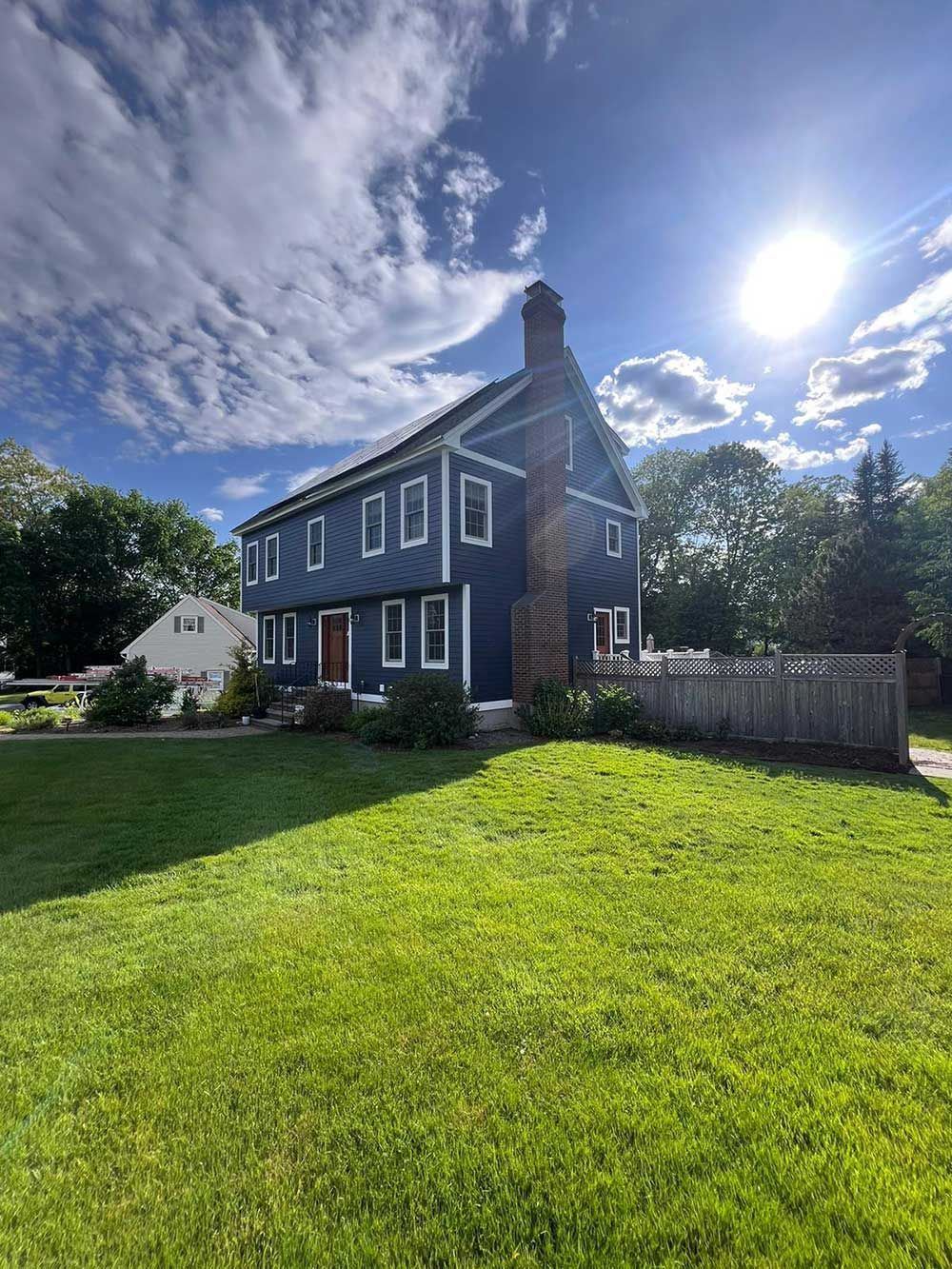 A large blue house with a large lawn in front of it.