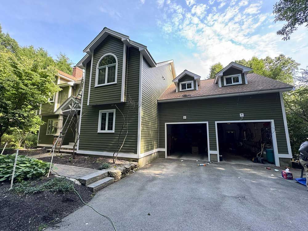 A large green house with a garage and stairs in front of it.