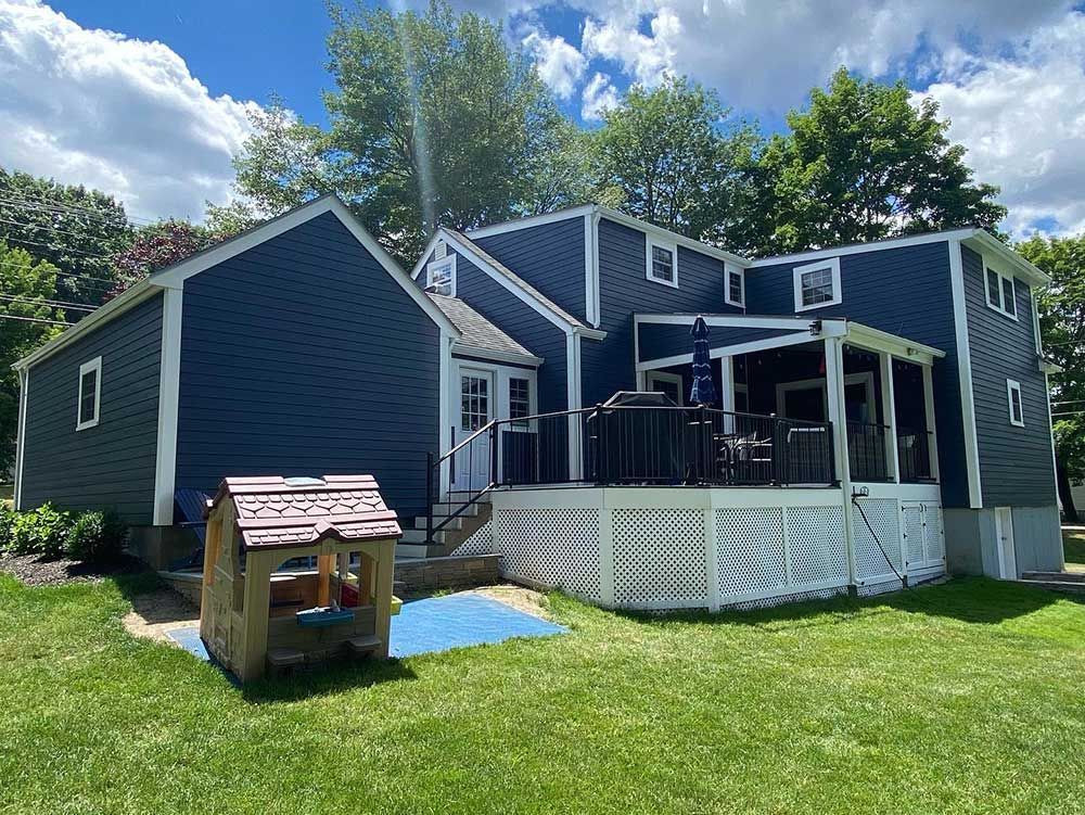 A blue house with a white deck and a playhouse in front of it.