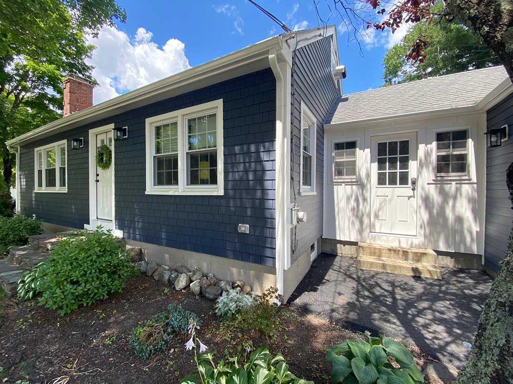 A house with a blue siding and white trim is for sale.