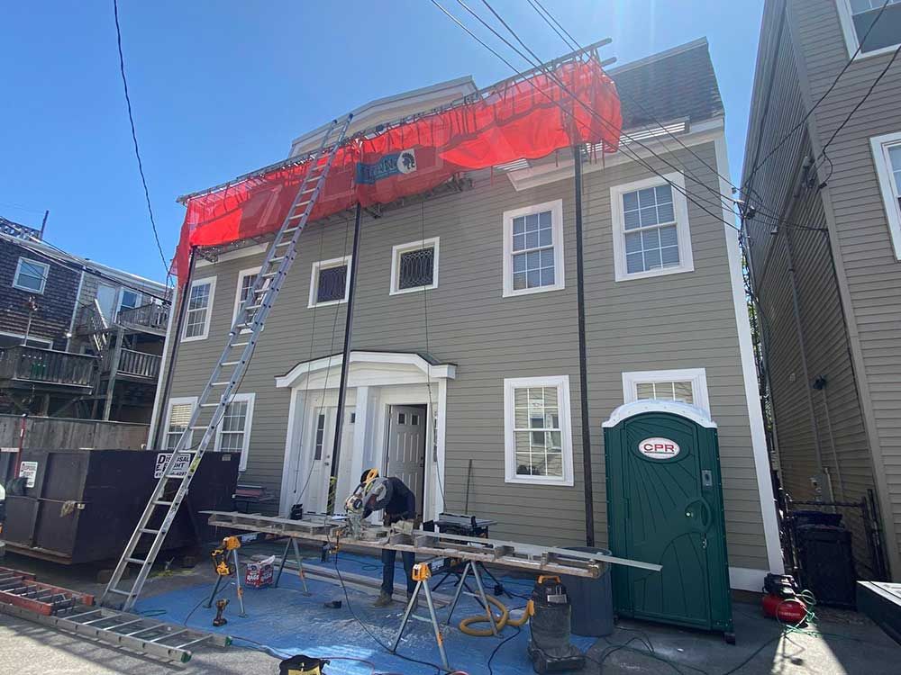 A man is standing on a ladder in front of a large building.