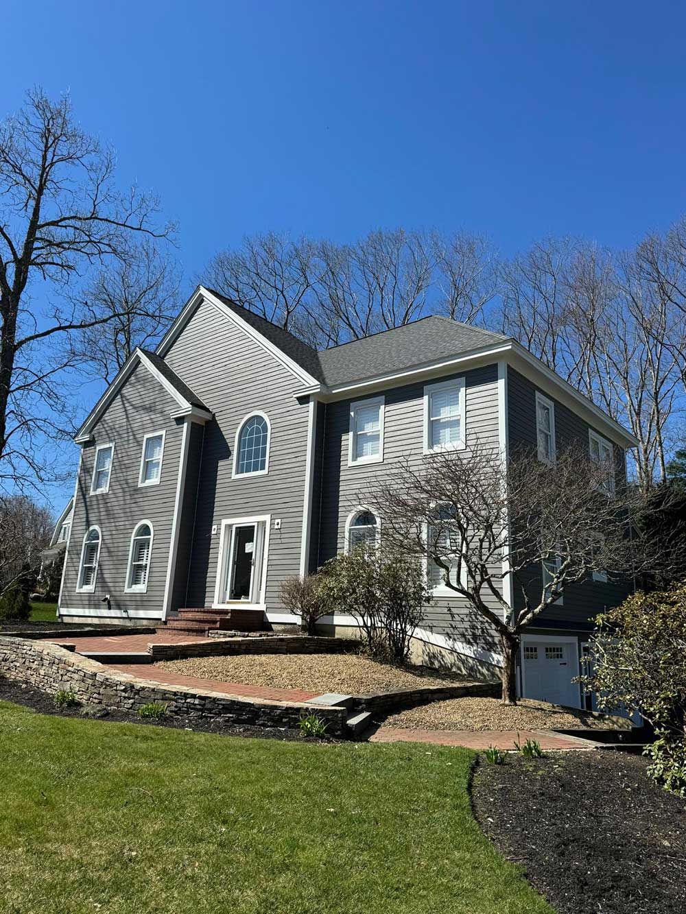 A large house with a lot of windows is sitting on top of a lush green hillside.