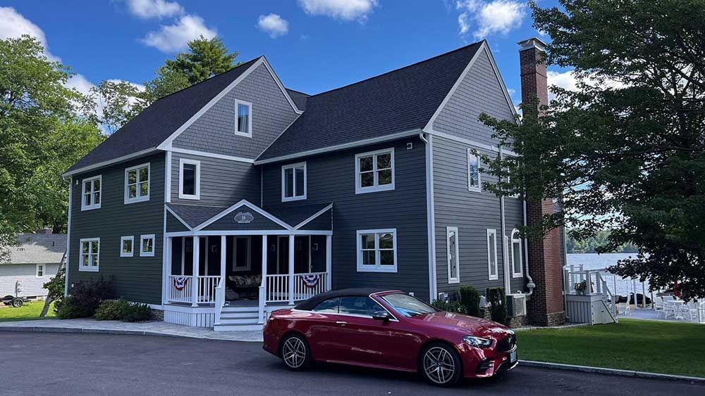 A red car is parked in front of a large house