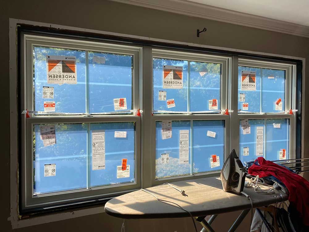 A room with a lot of windows and an ironing board.