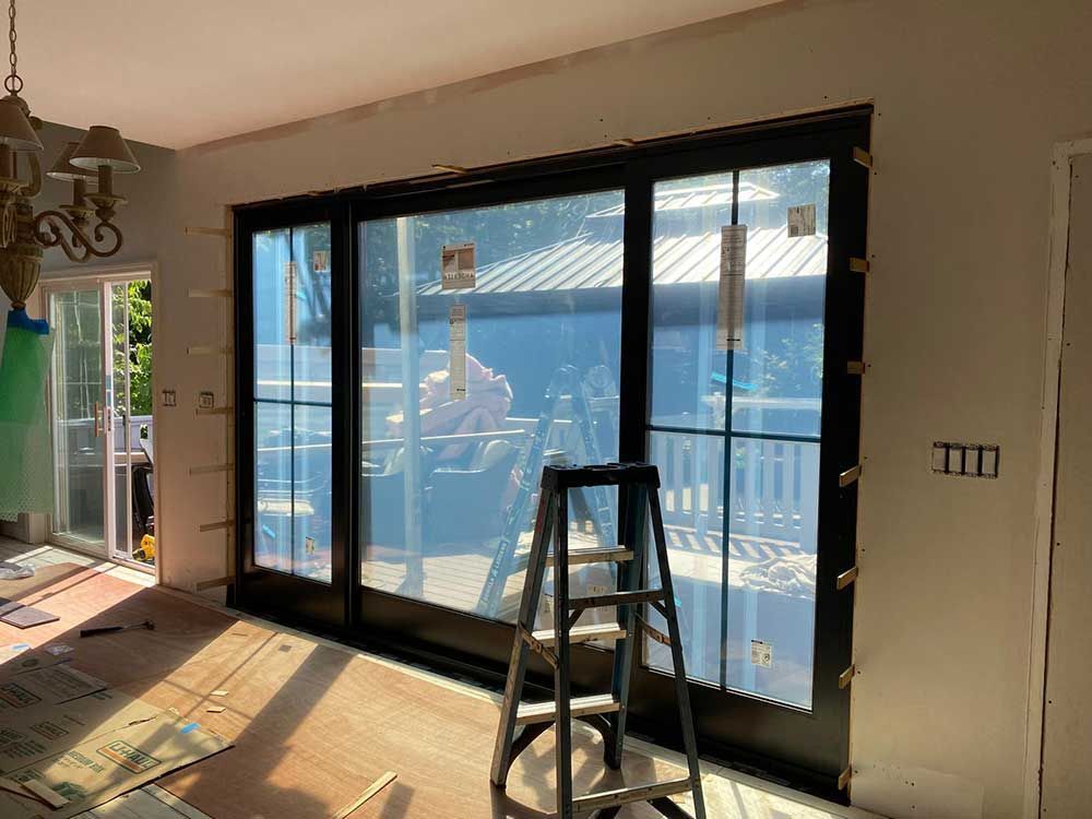 A ladder is sitting in front of a large window in a room.