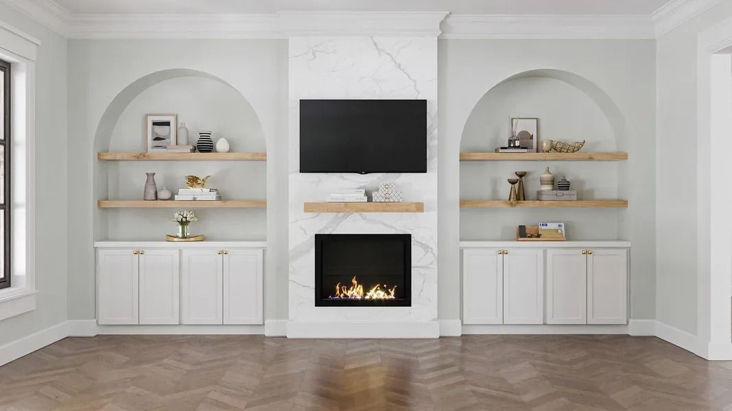 Living room with a fireplace, TV, built-in shelves, white cabinets, and light wood floors.
