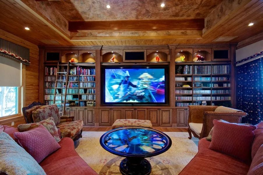 Cozy home theater with a large screen, built-in shelves, and comfortable seating in a room with wood paneling.