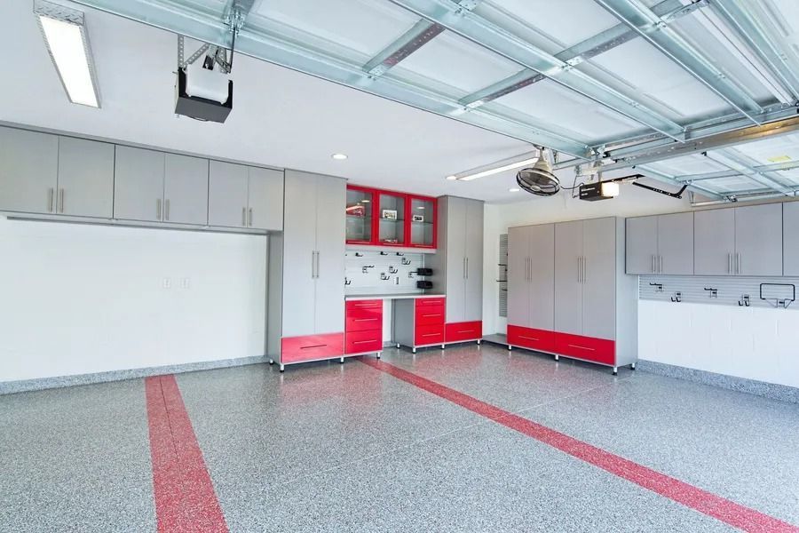 Garage with red and gray cabinets and a speckled floor.