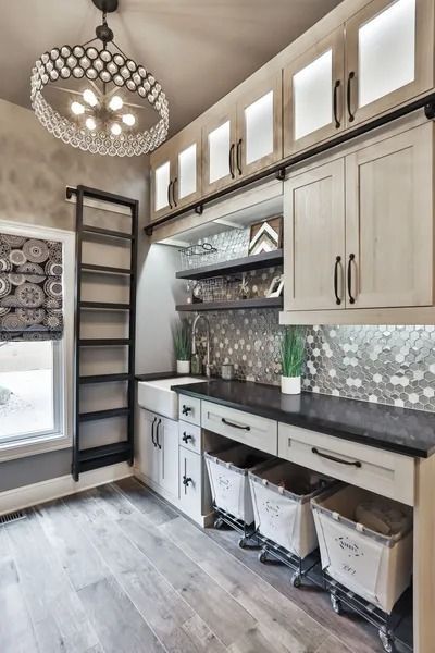 Stylish laundry room with white cabinets, gray countertops, and a decorative light fixture.