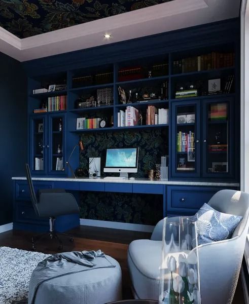 Blue home office with desk, bookshelf, and armchair. Dark ceiling, books, and decorations.