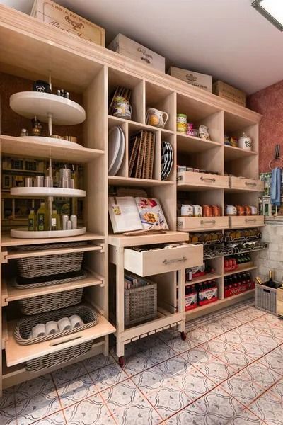 Wooden pantry filled with shelves, drawers, and turntables, stocked with food, dishes, and supplies.