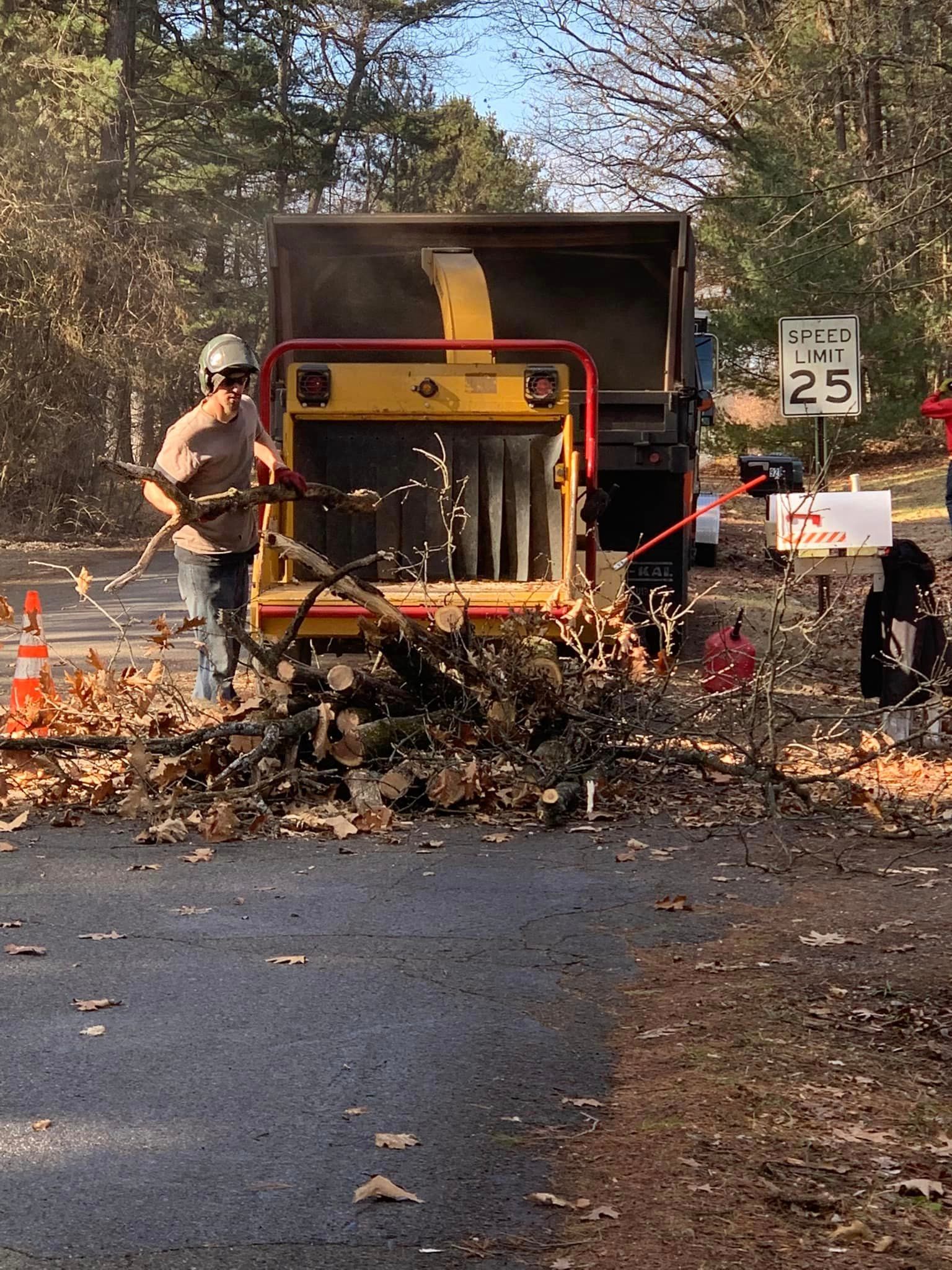 A man is using a machine to remove leaves from the road.