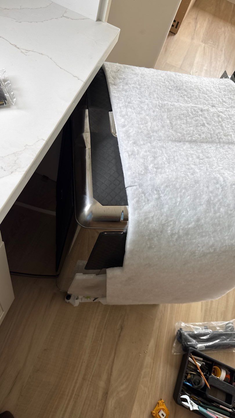 Damaged black-and-silver chair wedged beside a white desk, wrapped in bubble wrap on a wood floor.