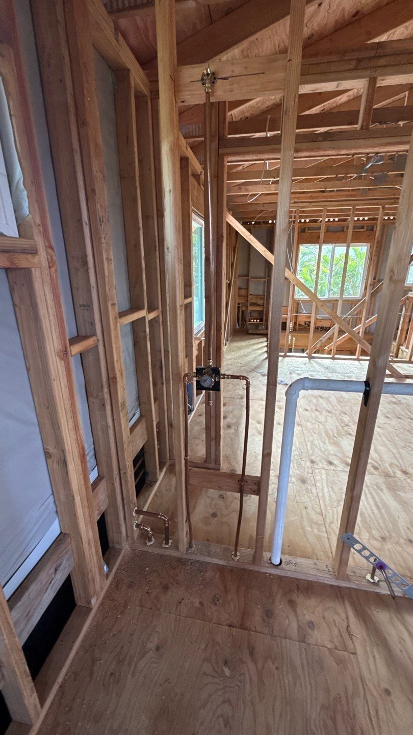 Interior of a house under construction with exposed wooden framing and a partially installed doorway.
