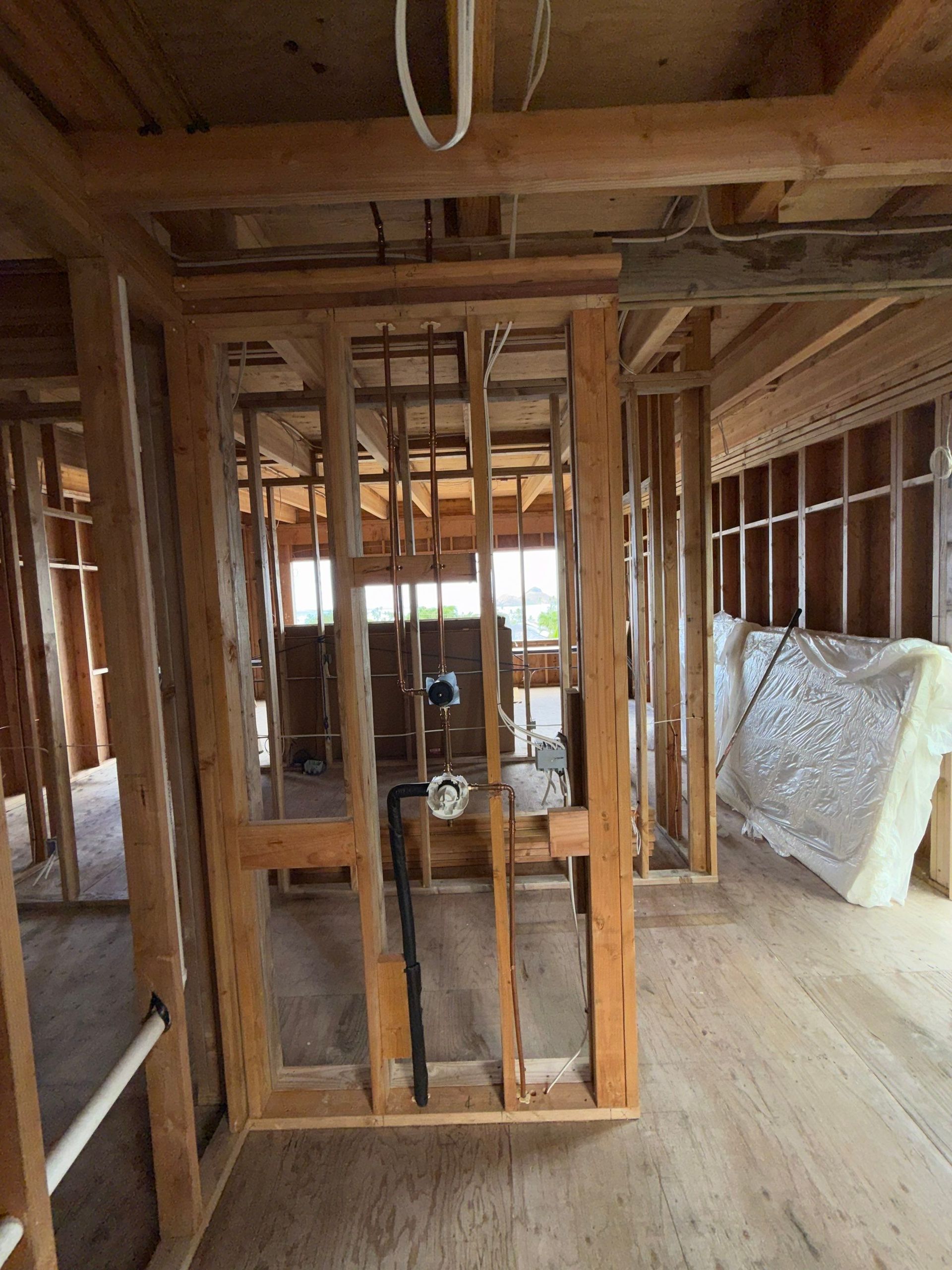 Interior under construction with exposed wood framing, unfinished walls, and a roll of insulation on the floor