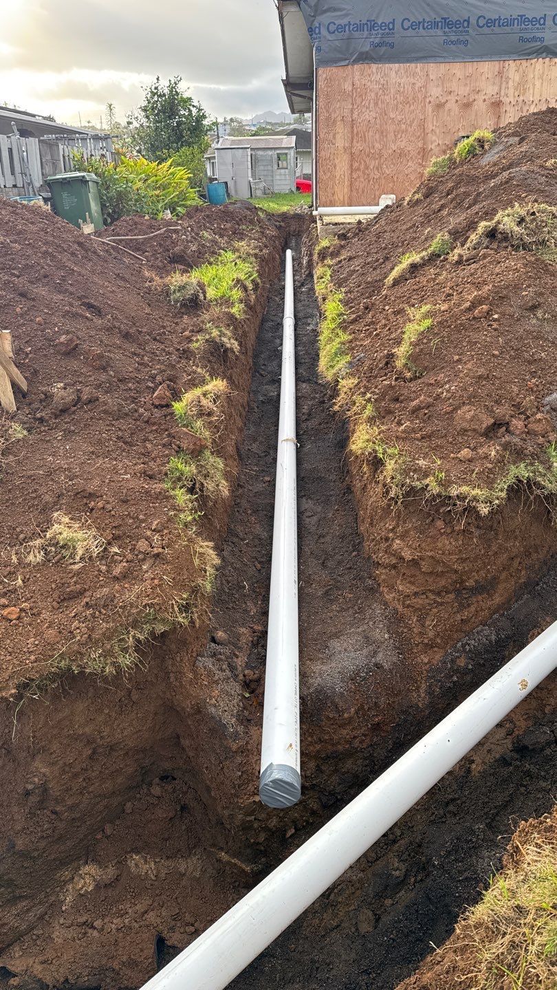 Open trench with white drainage pipes running through exposed soil at a construction site