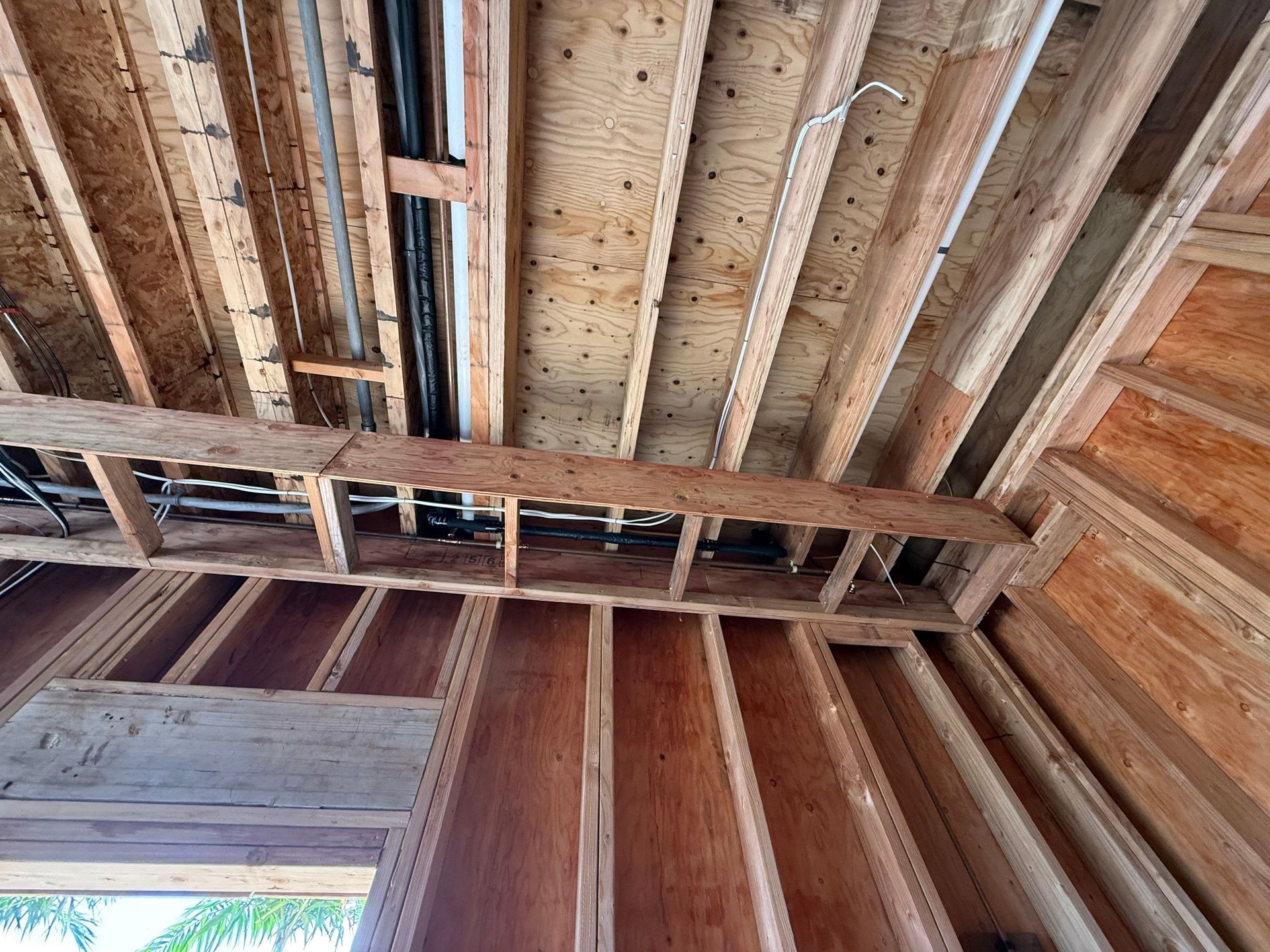 Interior of unfinished wooden room, showing exposed roof rafters and wall framing.