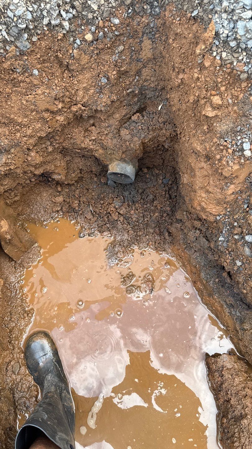 Mud-filled pothole in gravel road with a boot at the bottom edge