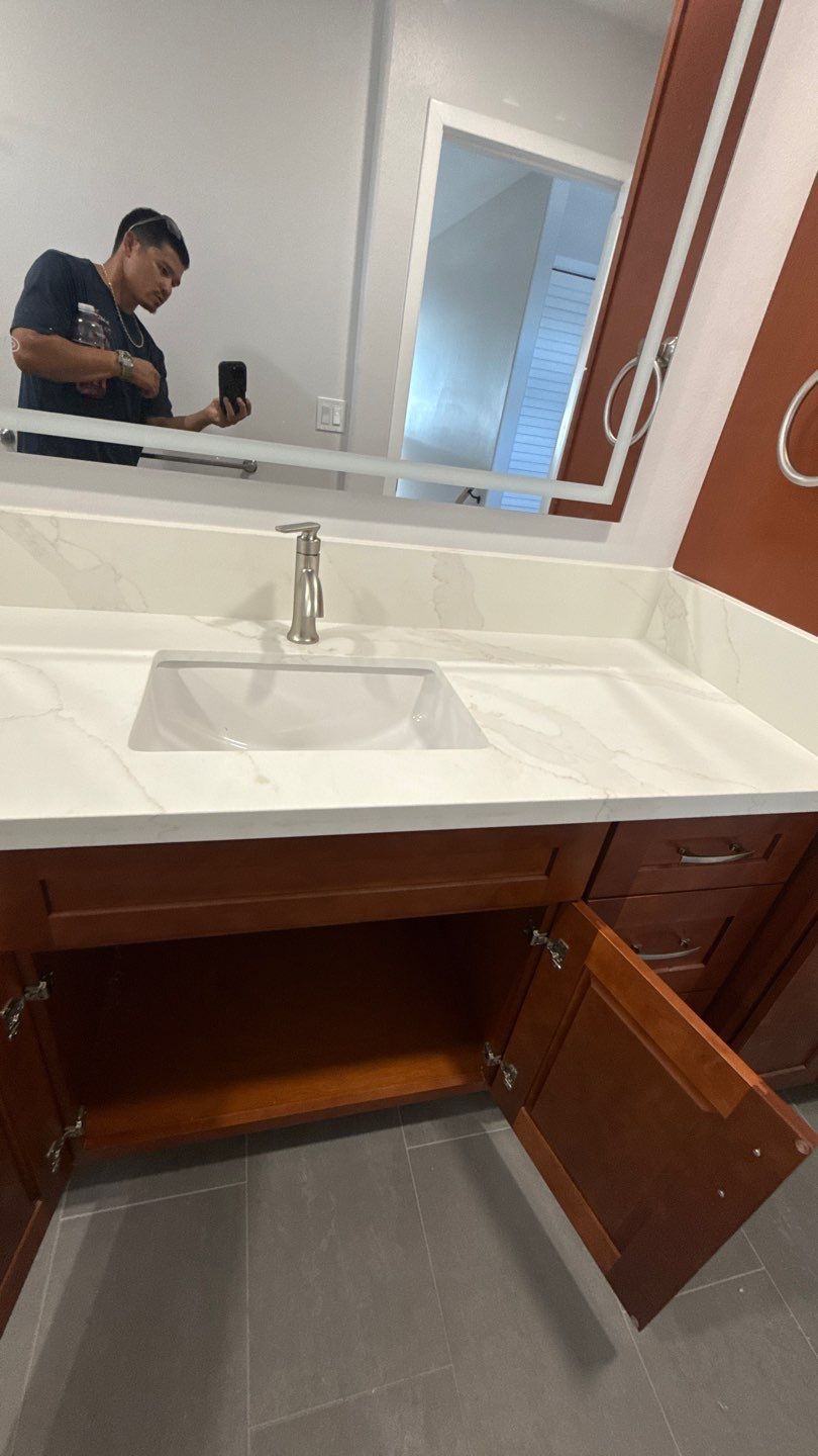 Bathroom vanity with white sink and mirror; open cabinet doors reveal storage space underneath.