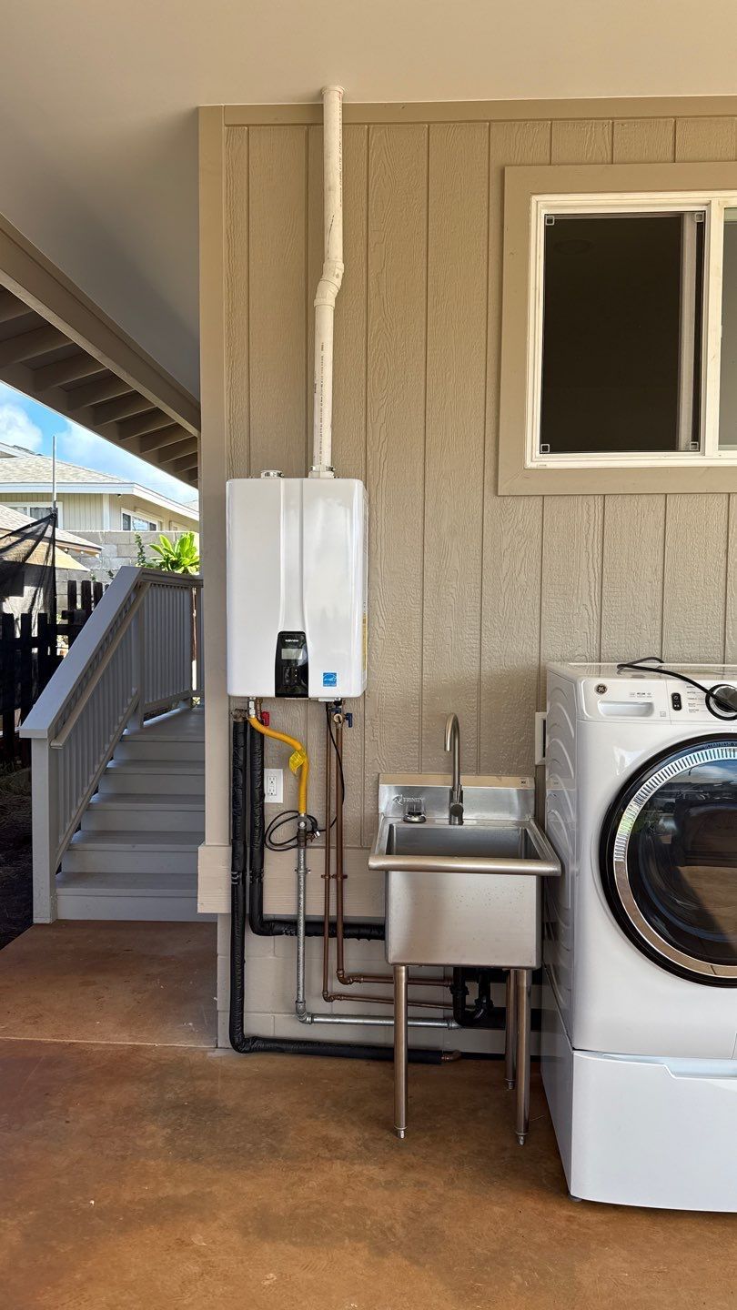 Laundry area beside a beige house with a utility sink, water heater, window, and washing machine on a covered patio