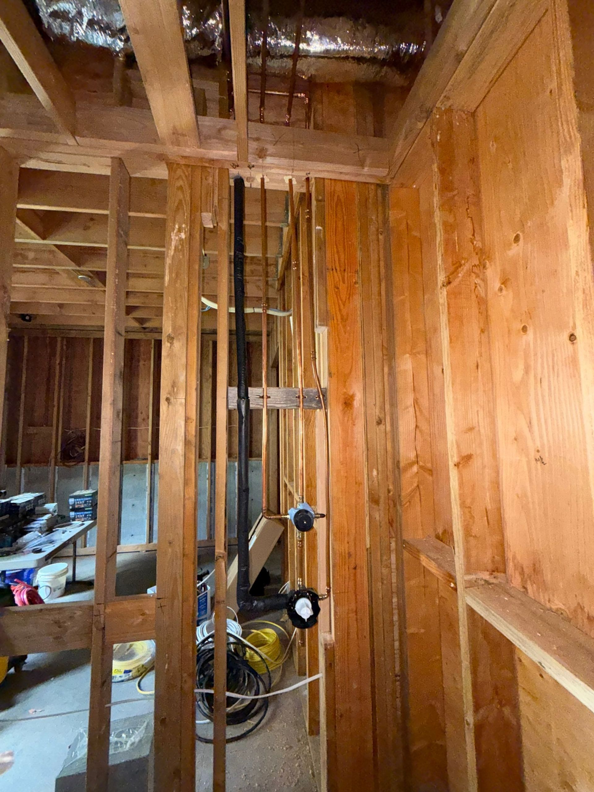 Unfinished wooden room with exposed studs, wiring, and a yellow bicycle in the corner.