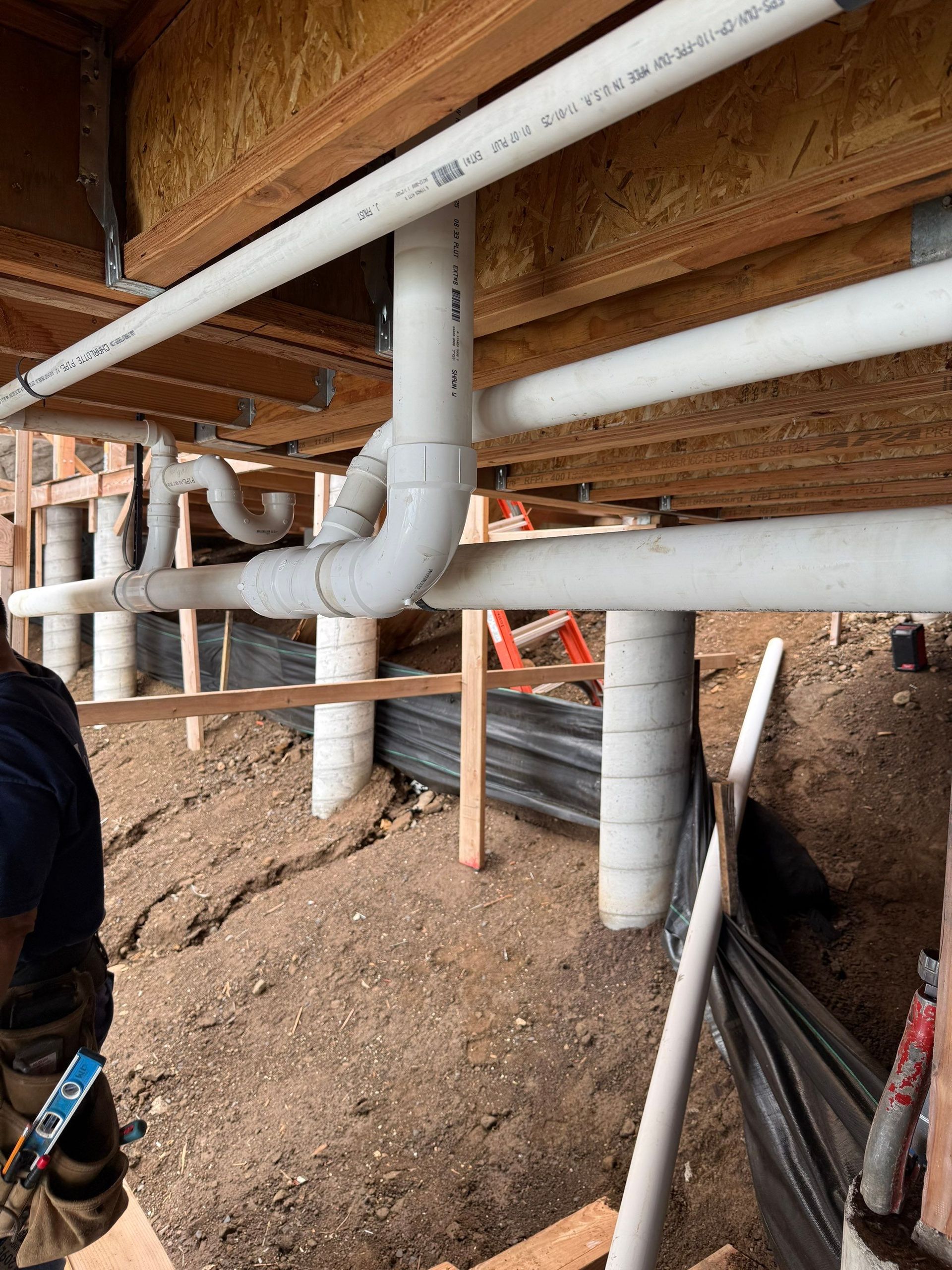 Plumbing pipes and ductwork under a house in a crawlspace during construction or repair