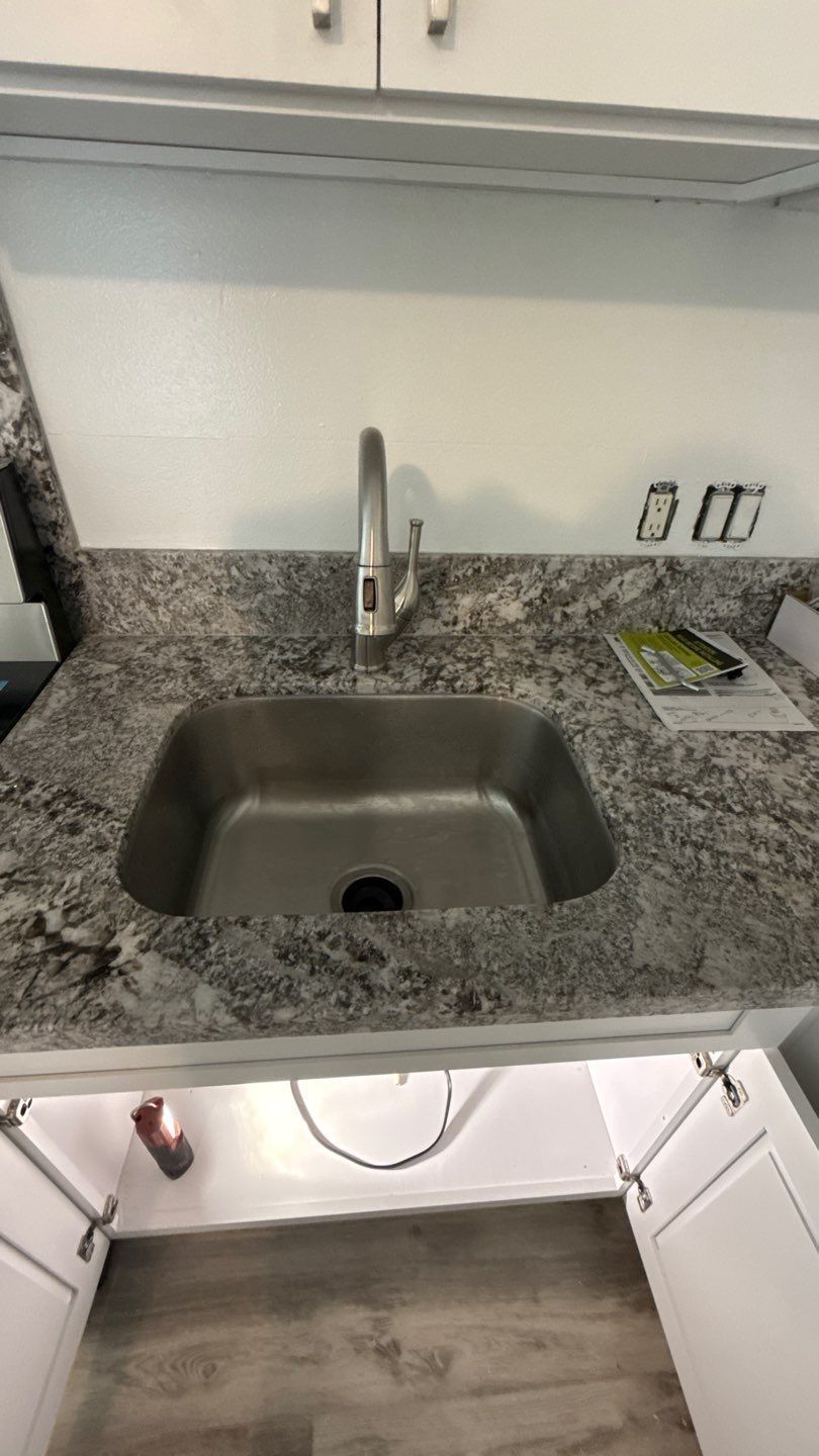 Stainless-steel sink with granite countertop and wall faucet in a small kitchen area