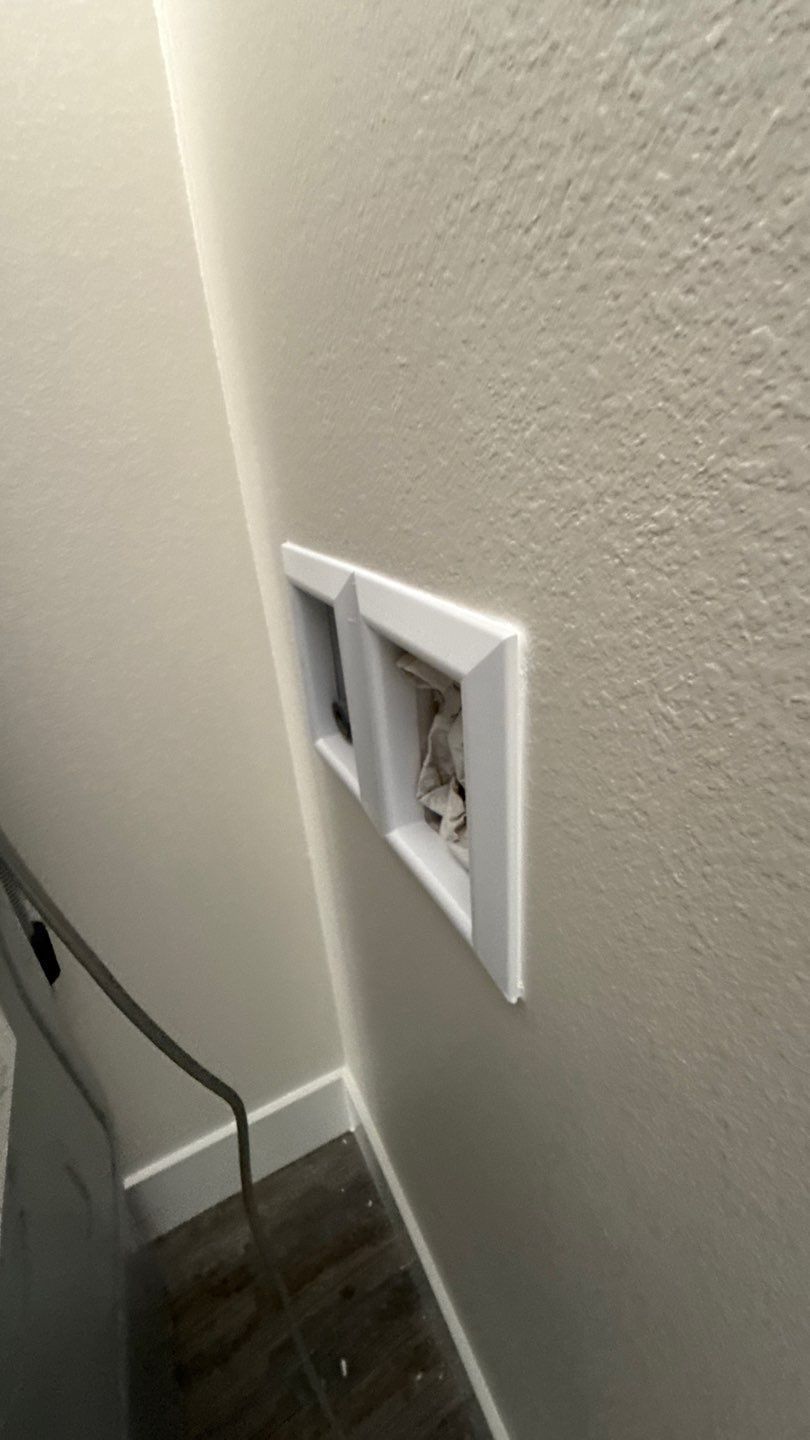 Wall outlet with a damaged faceplate on a beige interior wall near the floor.