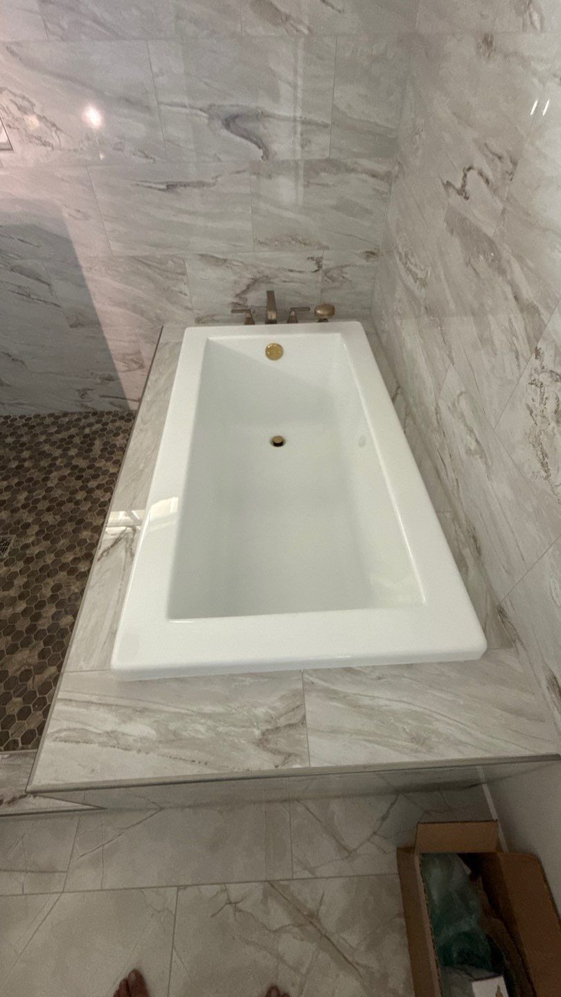 White bathroom sink set into a gray marble countertop with a faucet and drain visible.