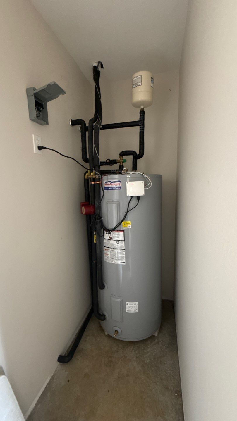 Gray water heater with pipes and vents in a small utility closet.
