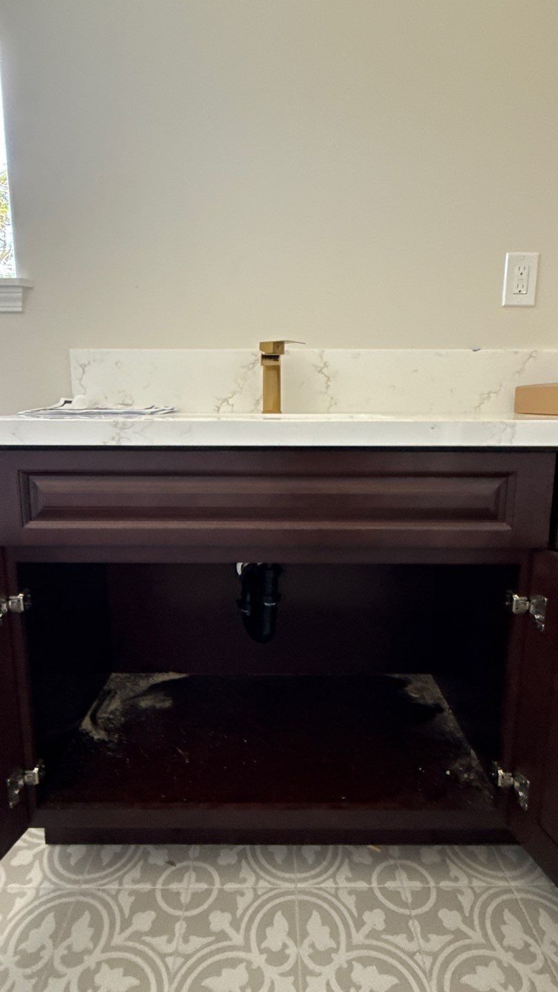 Dark wood bathroom vanity with white countertop and sink area against a beige wall